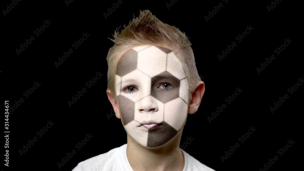Sad fan of the football team. A child with a face painted as football ball. Unhappy boy with sad eyes. Fiasco of your favorite team. Disappointment. Sadness. Experience. Failure. Bad luck. Sad fan of the football team. A child with a face painted as football ball. Unhappy boy with sad eyes. Fiasco of your favorite team. Disappointment. Sadness. Experience. Failure. Bad luck.