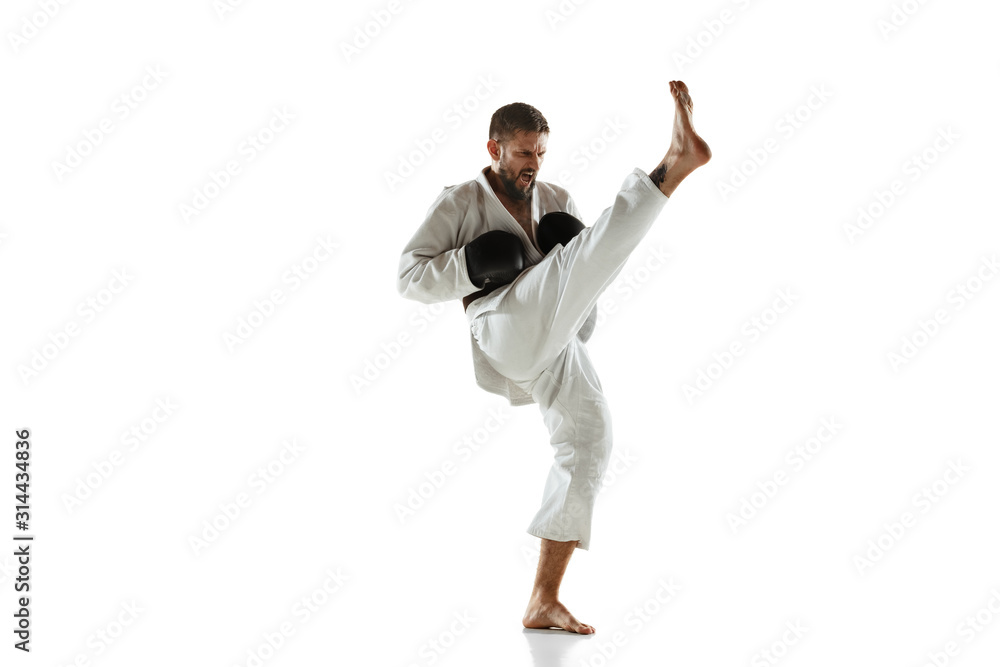 Confident coach in kimono practicing hand-to-hand combat, martial arts. Young male caucasian fighter with black belt training on white studio background. Concept of healthy lifestyle, sport, action. Confident coach in kimono practicing hand-to-hand combat, martial arts. Young male caucasian fighter with black belt training on white studio background. Concept of healthy lifestyle, sport, action.
