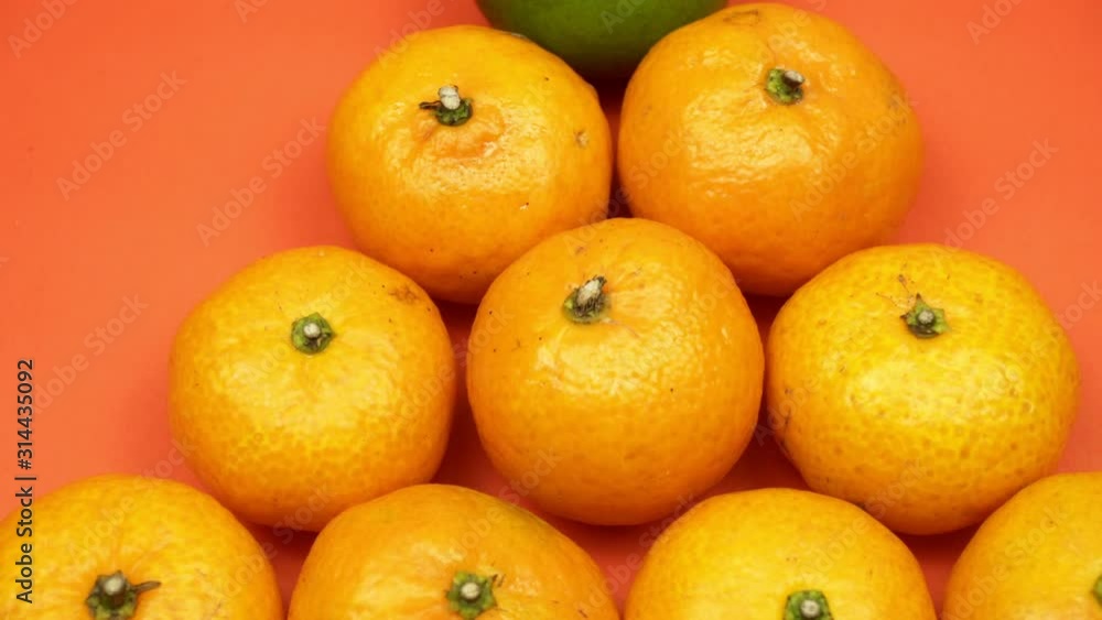 Small juicy orange tangerines close-up. Single grained mandarin among orange. Not like everyone else. A lot of juicy fruits on a bright background. Small juicy orange tangerines close-up. Single grained mandarin among orange. Not like everyone else. A lot of juicy fruits on a bright background.