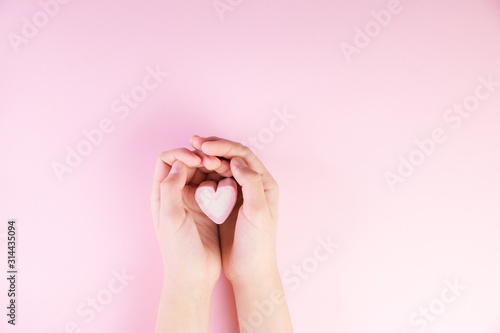 Pastel valentine background made of marshmallows souffle in the form of hearts on a pink background in hands. Valentine's Day concept with copy space