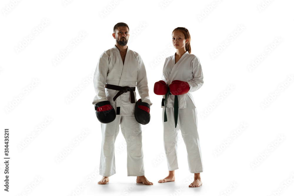 Junior in kimono hand-to-hand combat posing with coach, martial arts. Young female mongol fighter with green belt training on white studio background. Concept of healthy lifestyle, sport, action. Junior in kimono hand-to-hand combat posing with coach, martial arts. Young female mongol fighter with green belt training on white studio background. Concept of healthy lifestyle, sport, action.