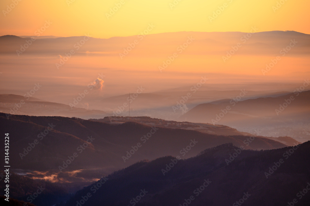 Sunrise in mountains, shape of hills in morning mist, white edit space