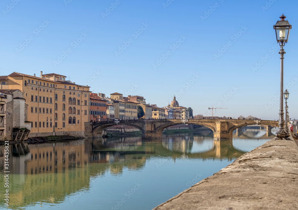 FLORENCE, ITALY, January 6, 2020: The River Arno in winter sunshine. Known as the Ponte Santa Trinita it is the oldest elliptic arch bridge in the world.