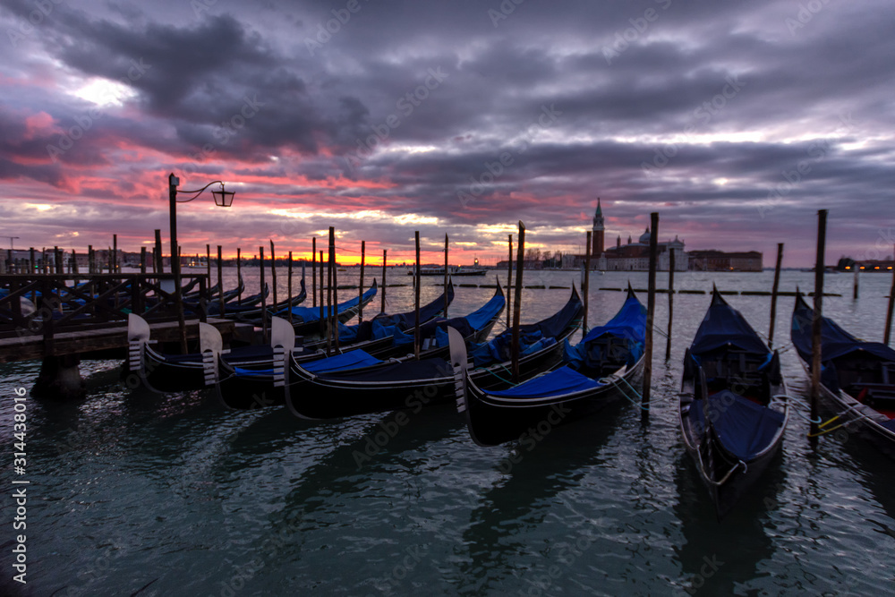Vibrant sunrise over the lagoon of Venice, Italy with gondolas