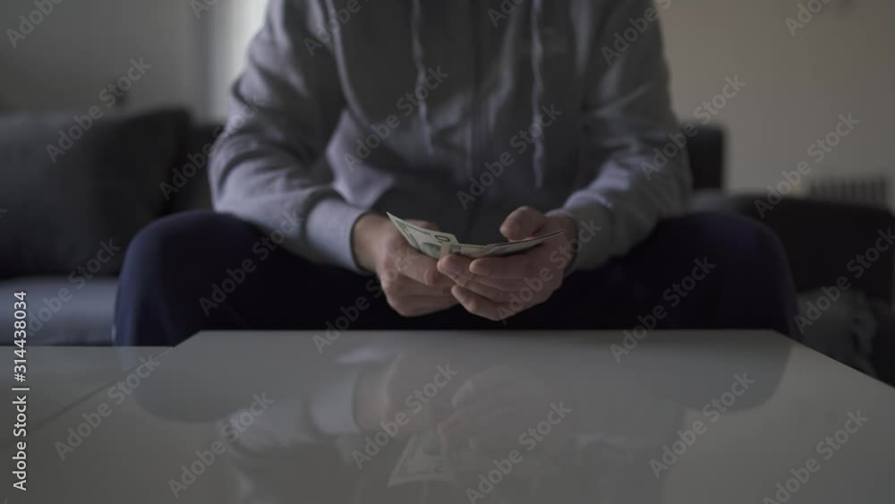 Midsection of unknown man picking up money US dollars banknotes from the table and counting it paying payday concept payment cash Midsection of unknown man picking up money US dollars banknotes from the table and counting it paying payday concept payment cash