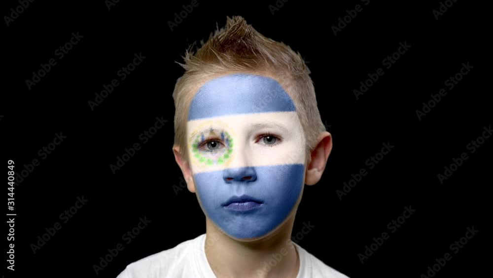 Sad fan of the football team of El Salvador. A child with a face painted in national colors. Unhappy boy with sad eyes. Fiasco of your favorite team. Disappointment. Sadness. Experience. Failure. Sad fan of the football team of El Salvador. A child with a face painted in national colors. Unhappy boy with sad eyes. Fiasco of your favorite team. Disappointment. Sadness. Experience. Failure.