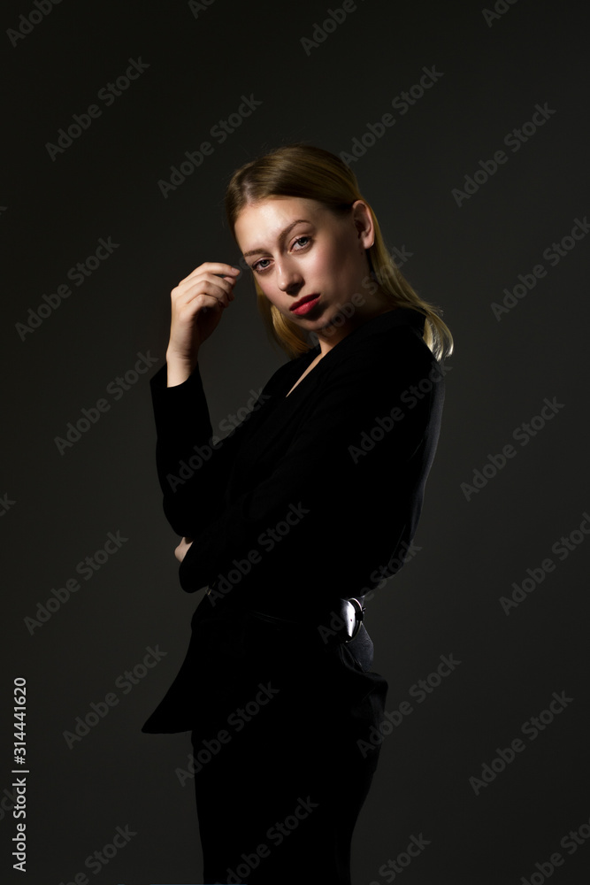 blonde in a black suit on a black background. Business woman blonde in a black suit on a black background. Business woman