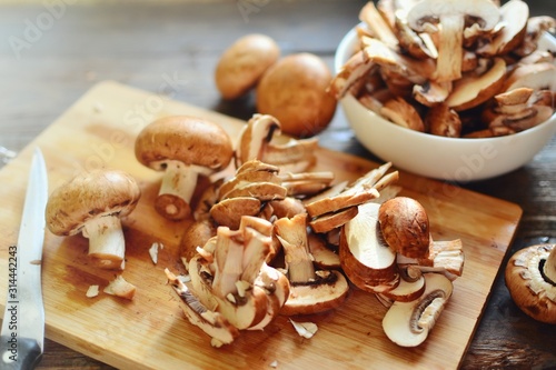 Royal fresh mushrooms on a wooden background. Sliced ​​champignons on a wooden board. Cooking process.