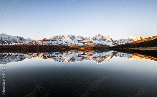Beautiful reflection of snow covered mountains at a lake in northern norway at sunrise