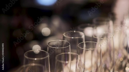 Close-up champagne glasses on the bartender table, the dinner restaurant, camera pan right to left with a bottle of champagne, indoor, close-up, focus