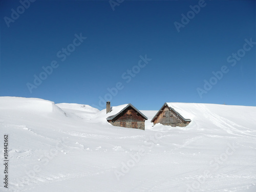 Huts in deep snow on the Alps under sunny sky - with copy-space