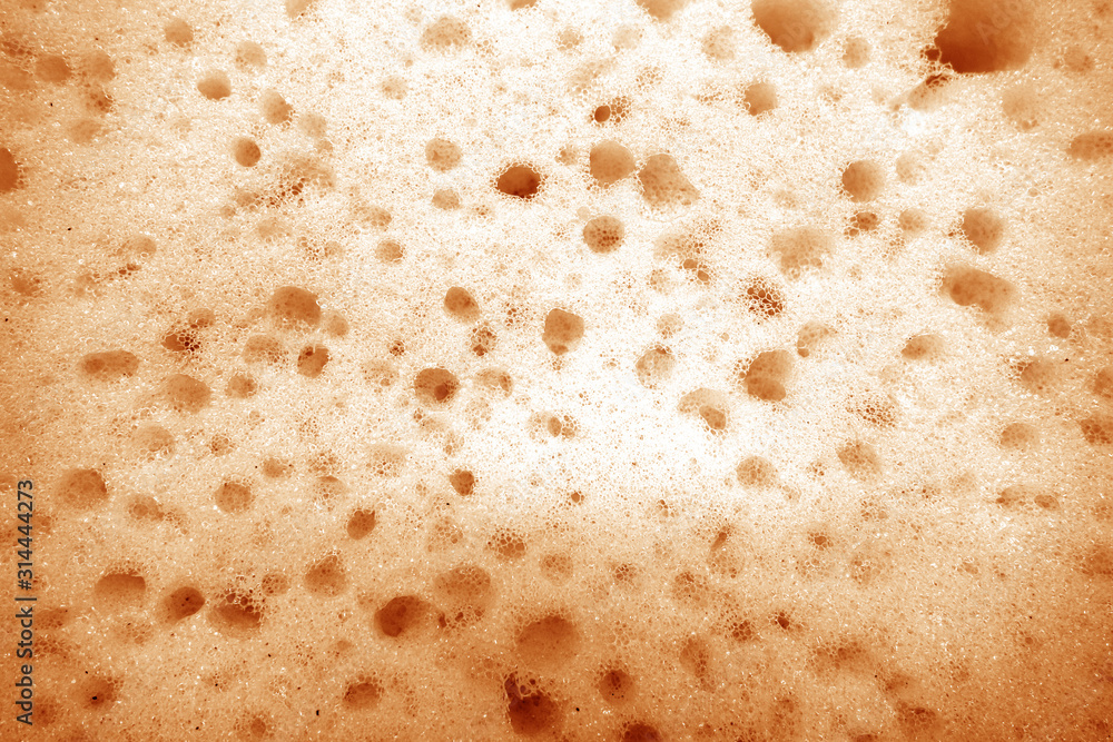 Cleaning sponge surface close up in orange tone. Cleaning sponge surface close up in orange tone.