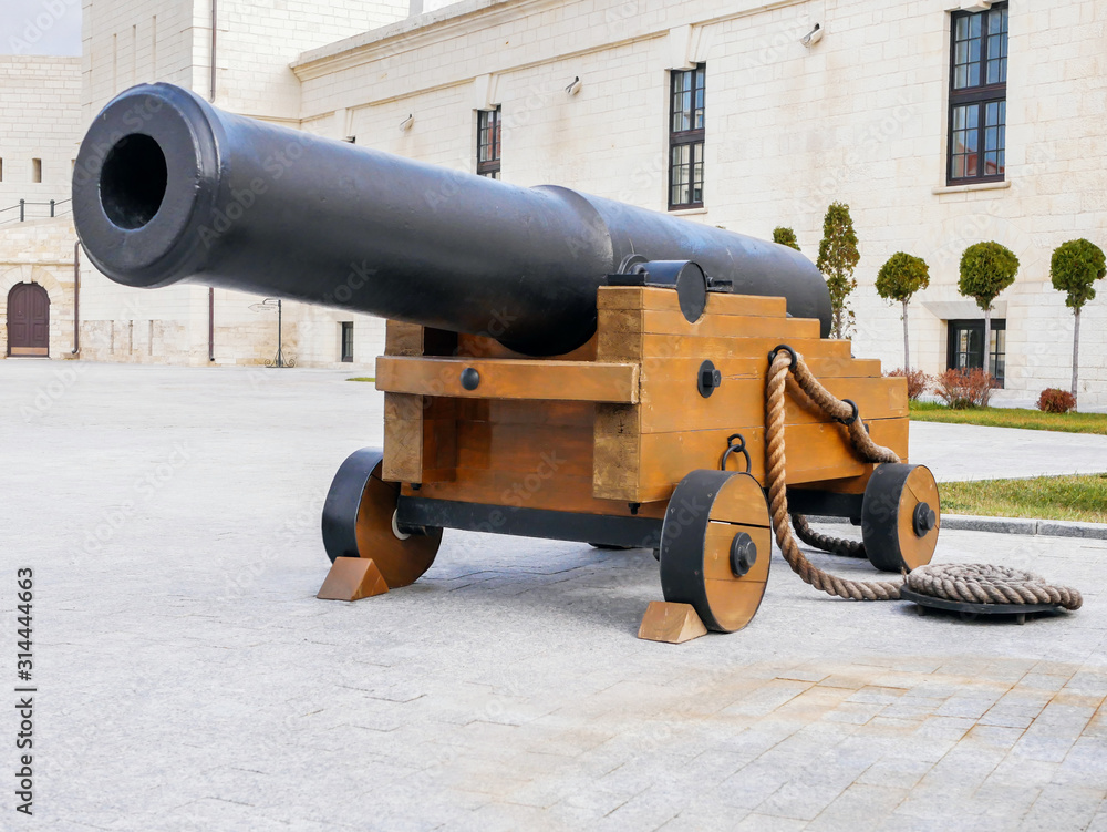 An old cast iron artillery gun on wooden wheels stands inside the fortress