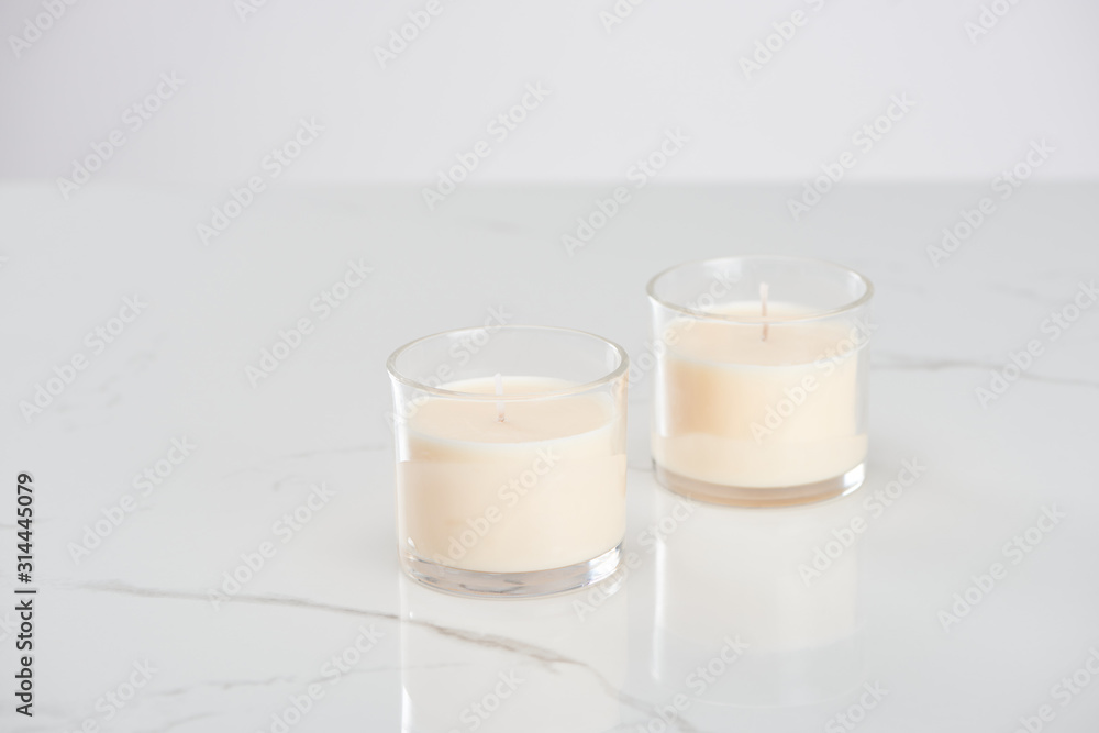 white candles in glass on marble white surface white candles in glass on marble white surface