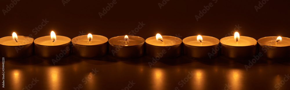 burning white candles glowing in dark, panoramic shot burning white candles glowing in dark, panoramic shot