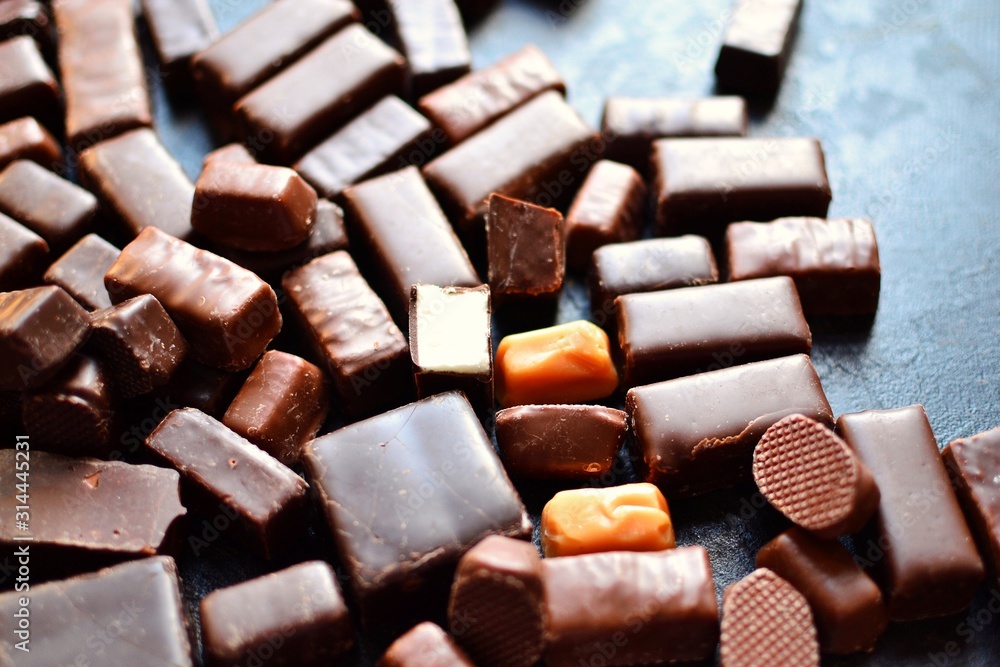 Assortment of chocolates. Candies on a dark bluish background. Top view place for text. Dark chocolate. Chocolate bars. Assortment of chocolates. Candies on a dark bluish background. Top view place for text. Dark chocolate. Chocolate bars.