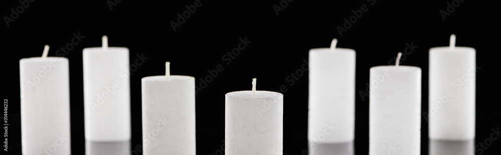 Naklejka premium selective focus of white candles isolated on black, panoramic shot