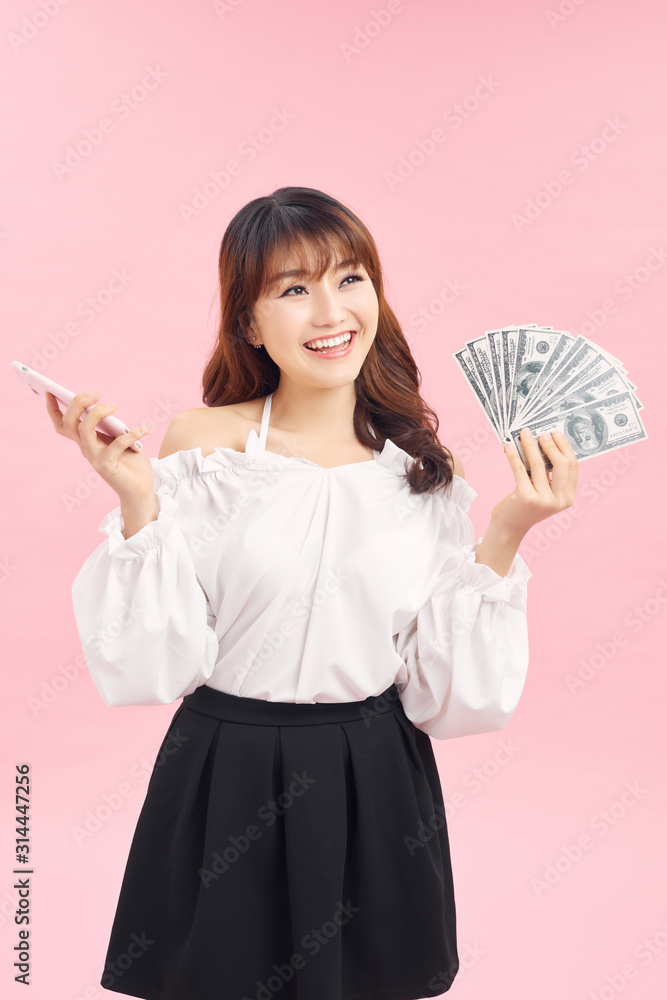 Portrait of young asian woman showing bunch of money banknotes on pink background Portrait of young asian woman showing bunch of money banknotes on pink background