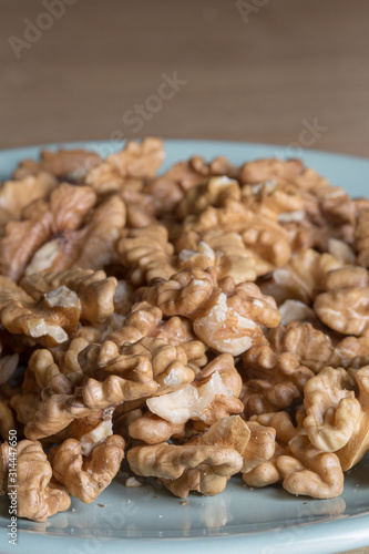 Many peeled walnuts on a blue plate close up still