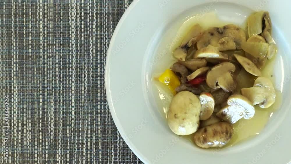 Mushrooms with sauce on a rotating plate. View from above. A plate of food is spinning on the table. Mushrooms with sauce on a rotating plate. View from above. A plate of food is spinning on the table.