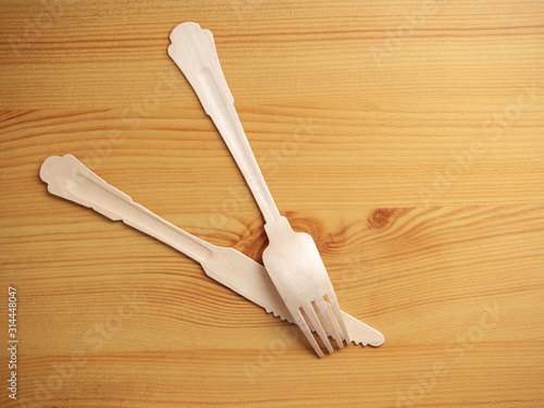 Wooden degradable fork and knife on a light wood table surface, Concept ecology and recycle issue.