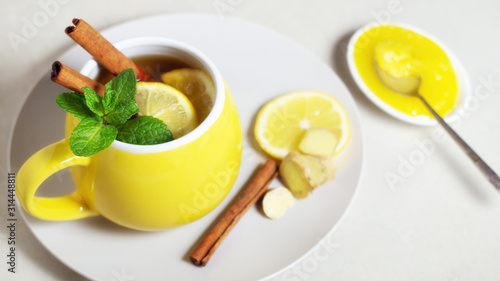 Tea with lemon, ginger, honey and cinnamon in a yellow cup
