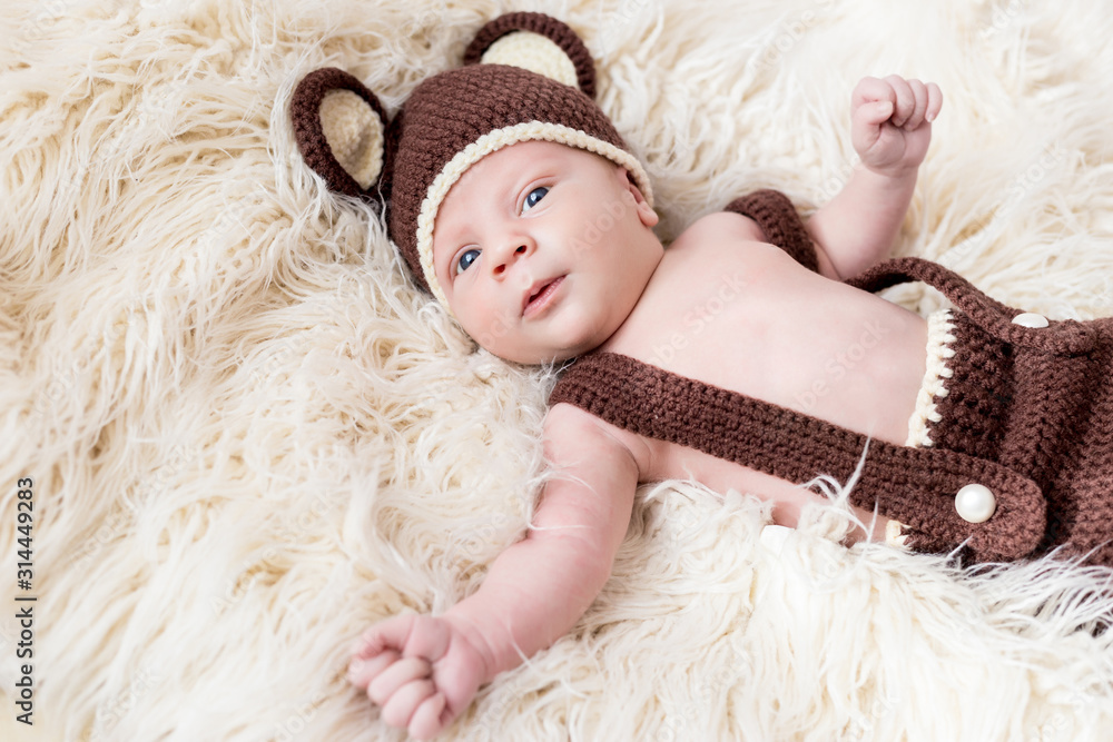 Cute little happy baby lies in a bear costume on a white background. newborn in a hat with ears on a white background Cute little happy baby lies in a bear costume on a white background. newborn in a hat with ears on a white background
