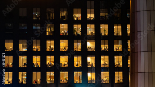 Office building exterior at night with interior lights on. Empty offices.