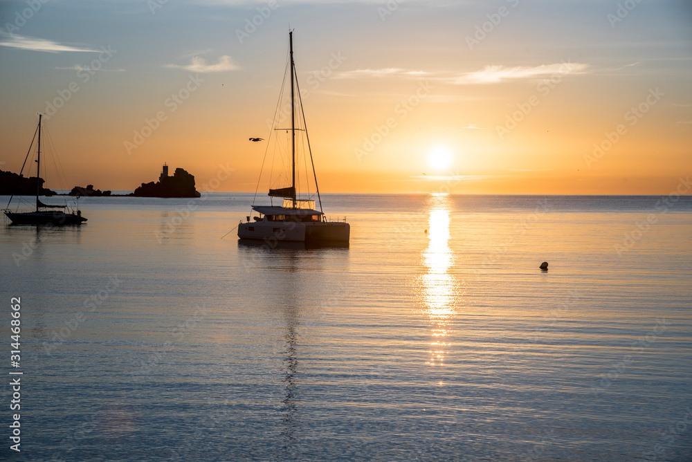 Sunrise at sea with catamaran docked at the mouth of the port