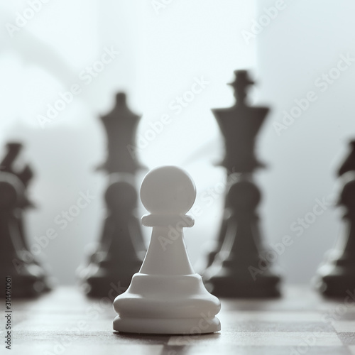 Single pawn against many enemies as a symbol of difficult unequal fight or struggle of minorities. Background in blur.