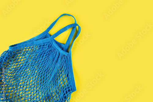 Blue reusable mesh on a yellow background. Ecological concept. Caring for the environment and rejection of plastic.