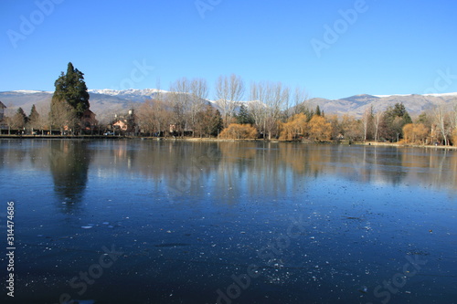 A blue lake covered with a thin layer of ice. the mountains. blue sky