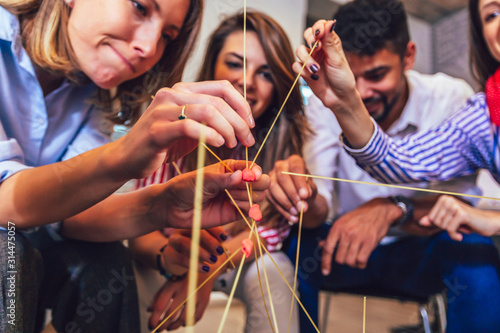 Happy friendly business team having fun at corporate training, funny teambuilding activity, playing spaghetti game. photo
