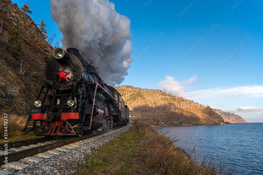 Fototapeta premium An old steam train travels by rail along Lake Baikal
