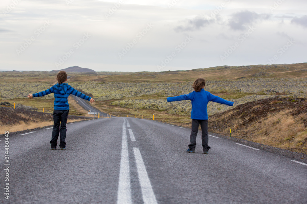 Obraz premium Kids running on an empty road in beautiful nature in Snaefellsjokull National Park in Iceland, autumntime