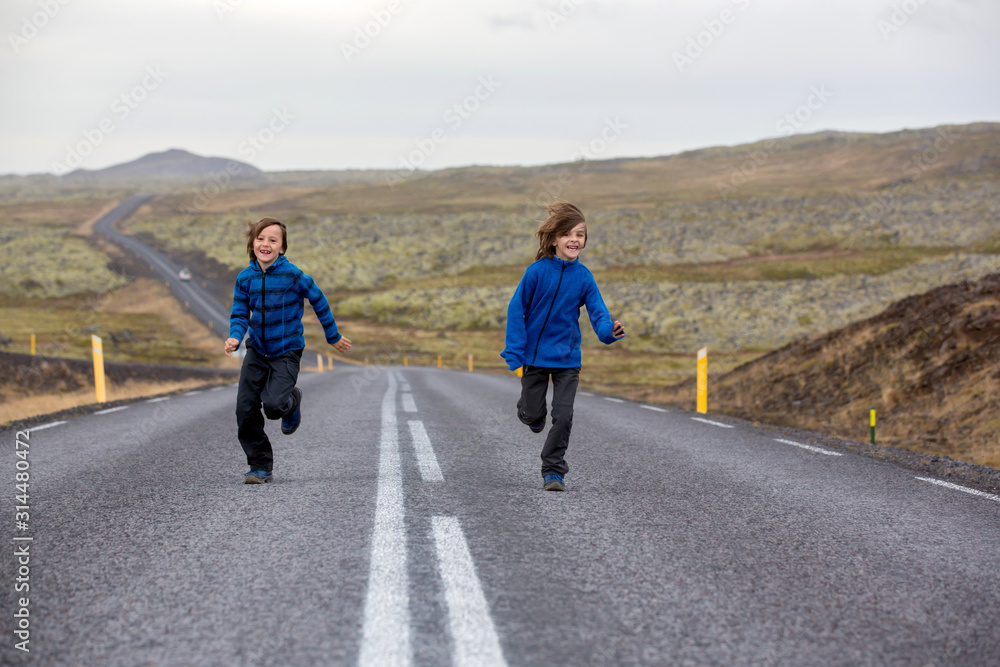 Kids running on an empty road in beautiful nature in Snaefellsjokull National Park in Iceland, autumntime Kids running on an empty road in beautiful nature in Snaefellsjokull National Park in Iceland, autumntime