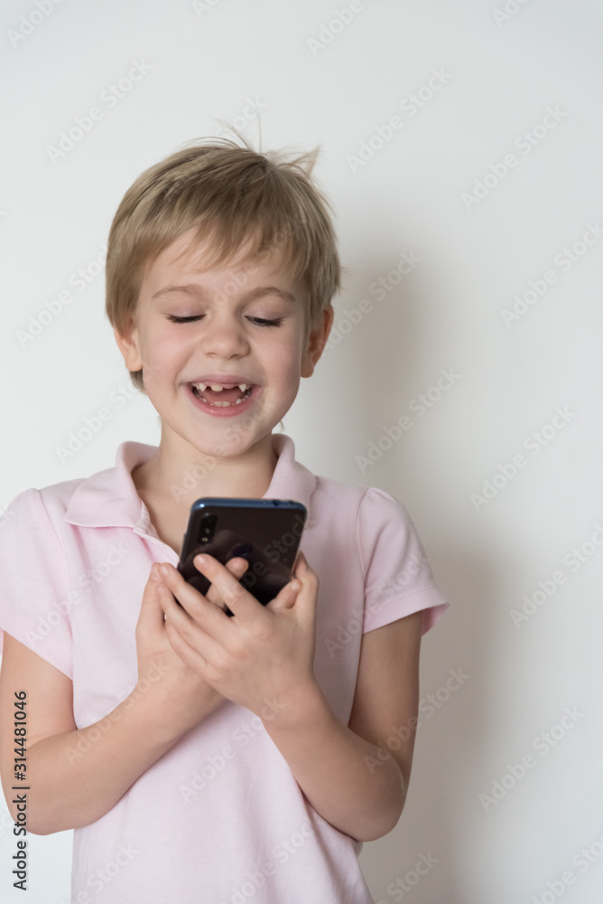 A cute child is laughing loudly, holding a cell phone in his hand. A cute child is laughing loudly, holding a cell phone in his hand.