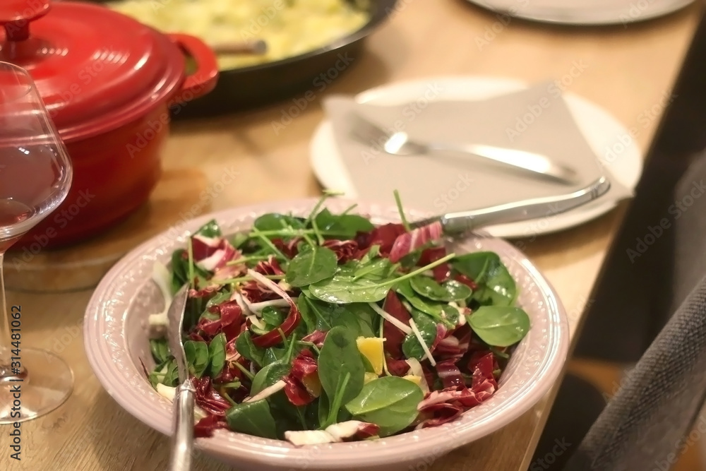Spinach, chicory, fennel and orange salad served on the festive table setting. Selective focus. Spinach, chicory, fennel and orange salad served on the festive table setting. Selective focus.