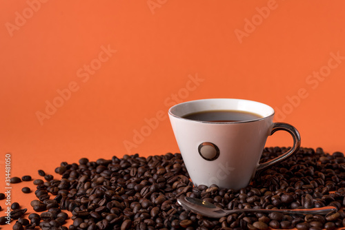 cup of aromatic coffee and coffee beans on an orange trendy background with space for text