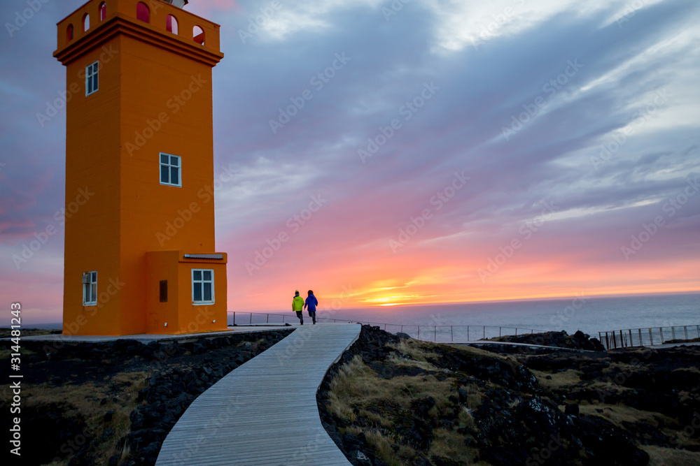 Children running on a path to lighthouse in lava field in beautiful nature in Snaefellsjokull National Park in Iceland, autumntime Children running on a path to lighthouse in lava field in beautiful nature in Snaefellsjokull National Park in Iceland, autumntime
