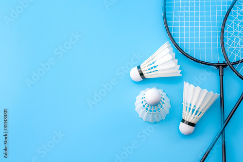 Obraz na płótnie Competitive sports and high performance in tournament match conceptual idea with badminton rackets and shuttlecock (birdie) isolated on blue court background with copy space w salonie
