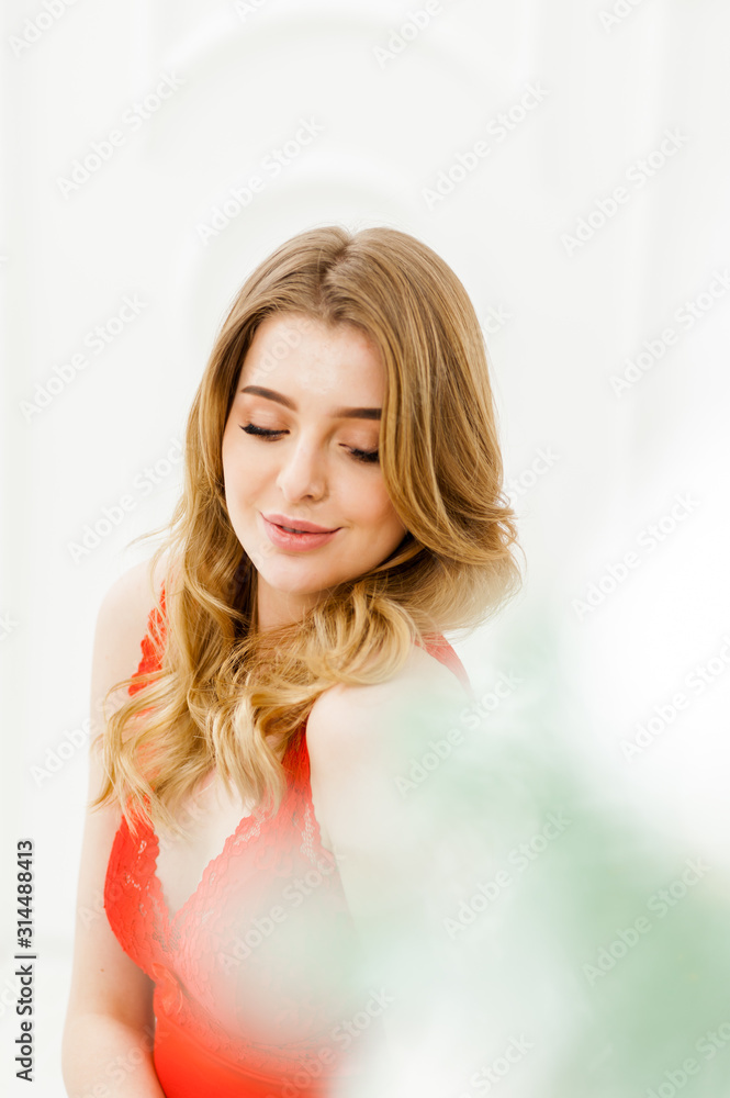 Sensual portrait of blonde woman in red lingerie indoor
