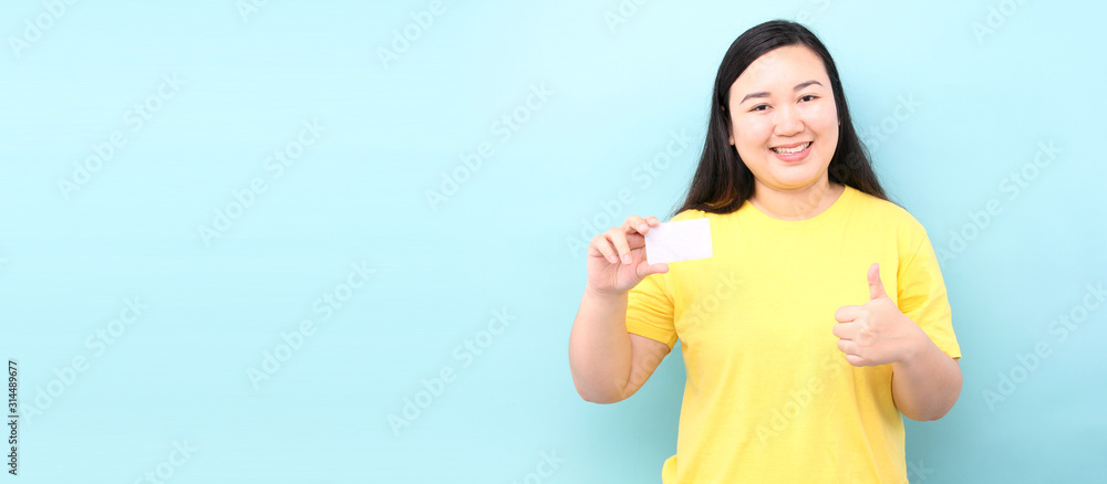 asian woman holding credit card happy with big smile doing ok sign, thumb up with fingers, excellent sign, on a blue background in studio With copy space. asian woman holding credit card happy with big smile doing ok sign, thumb up with fingers, excellent sign, on a blue background in studio With copy space.