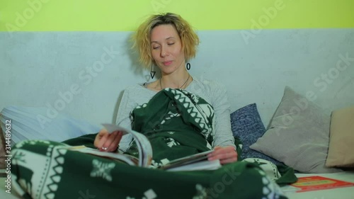 Jolly woman sitting on a sofa leafing through a book. photo