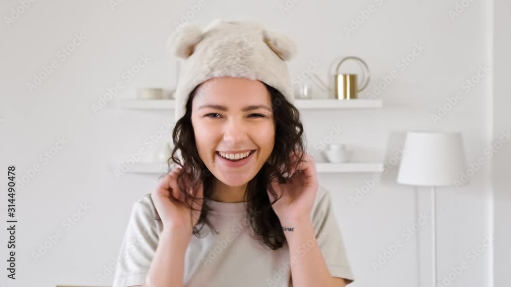 Portrait of a young woman looking at the camera in a funny hat smiling and fooling around and shows language. Portrait of a young woman looking at the camera in a funny hat smiling and fooling around and shows language.