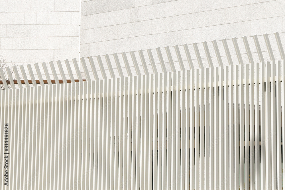 A white metal fence with white building in the background. A white metal fence with white building in the background.