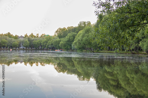 Yaroslavl. Warm evening in Neftyanik Park. Park refinery. Reflection of colorful sunset in the lake. Peace and quiet surrounded by green trees photo