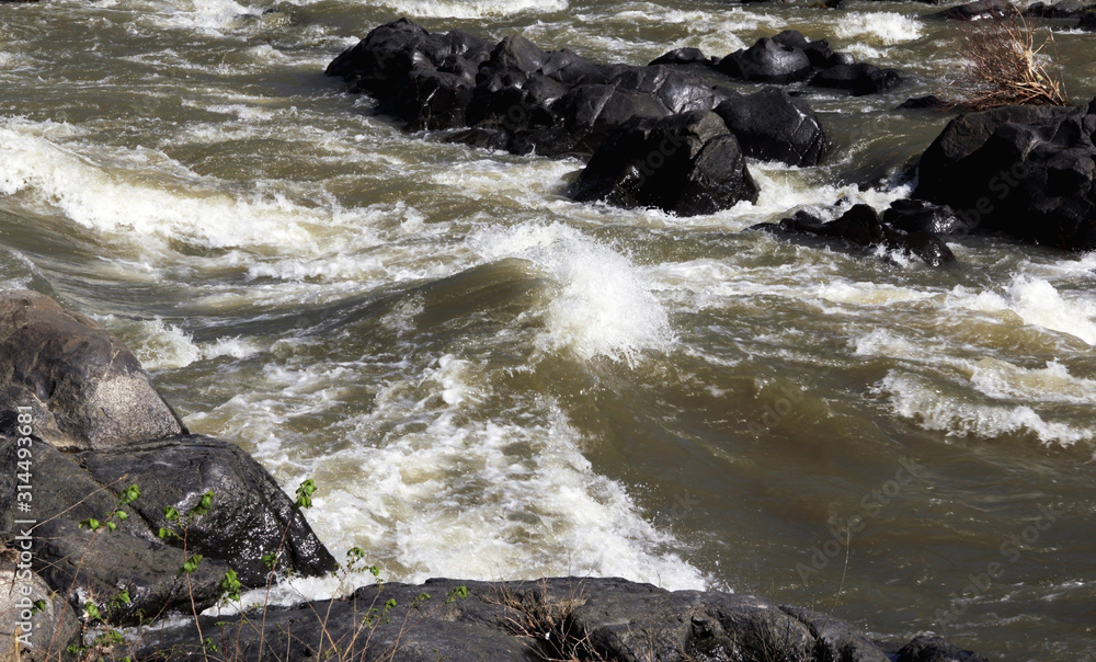 Waves of a mountain stream with rocks in the background. Waves of a mountain stream with rocks in the background.