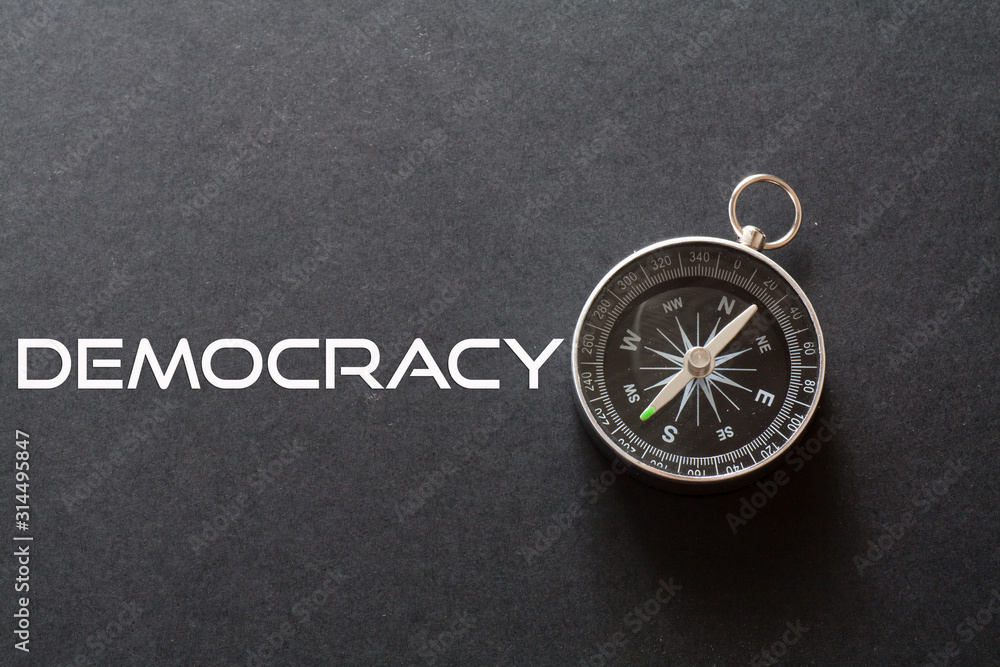 Democracy word written on black background with compass Democracy word written on black background with compass