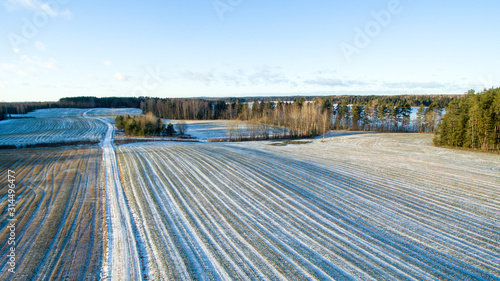 Aerial view over snowy winter landscape with the fields, forest and frozen lake Hino in Võru county, Southern Estonia